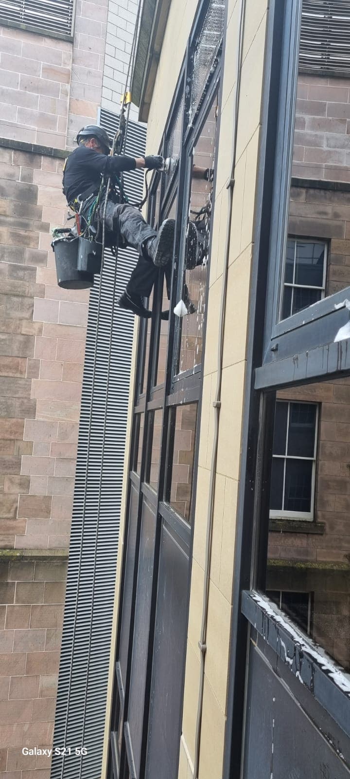 Rope access technician cleaning commercial windows