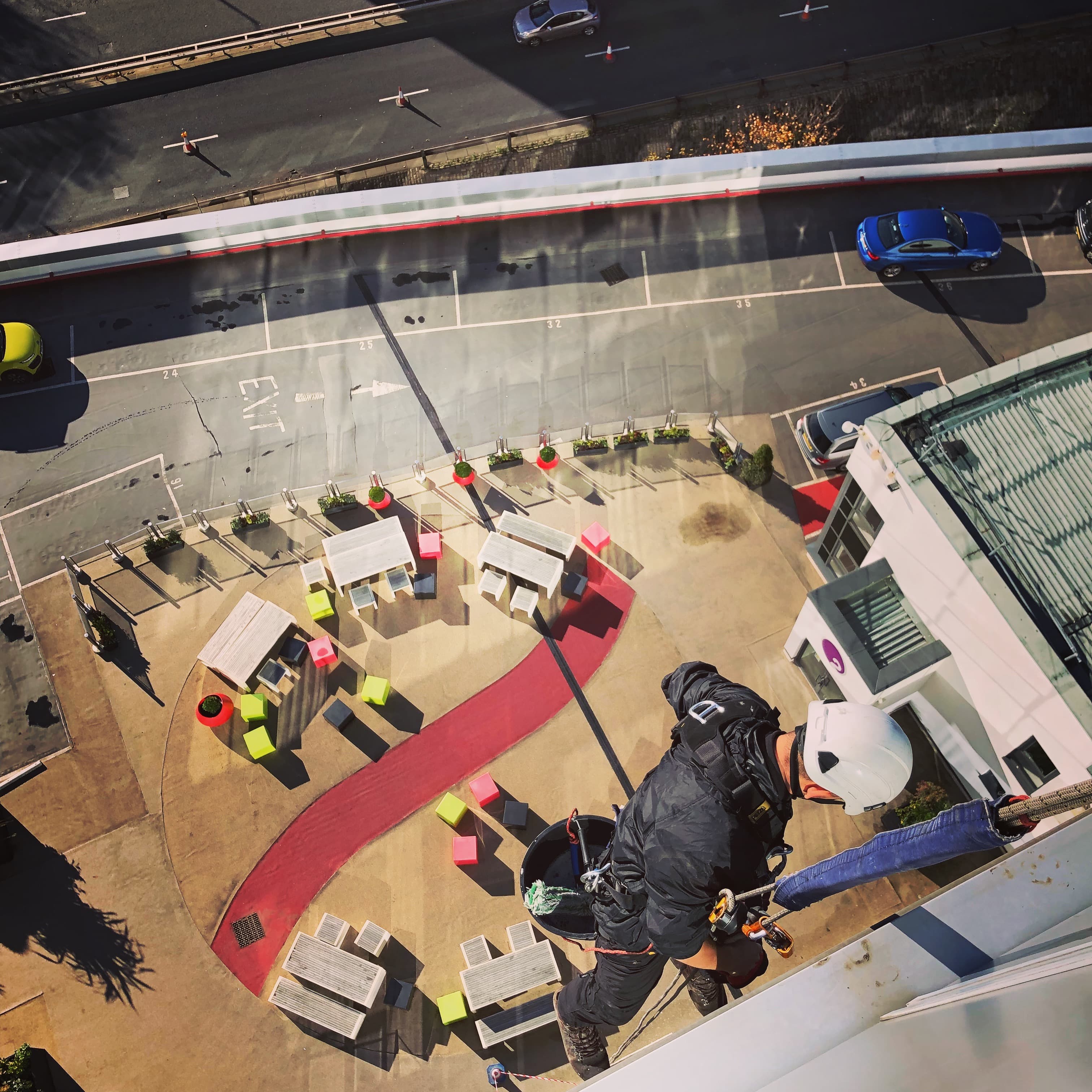 Aerial view of IRATA rope access technician working at height on Glasgow commercial building