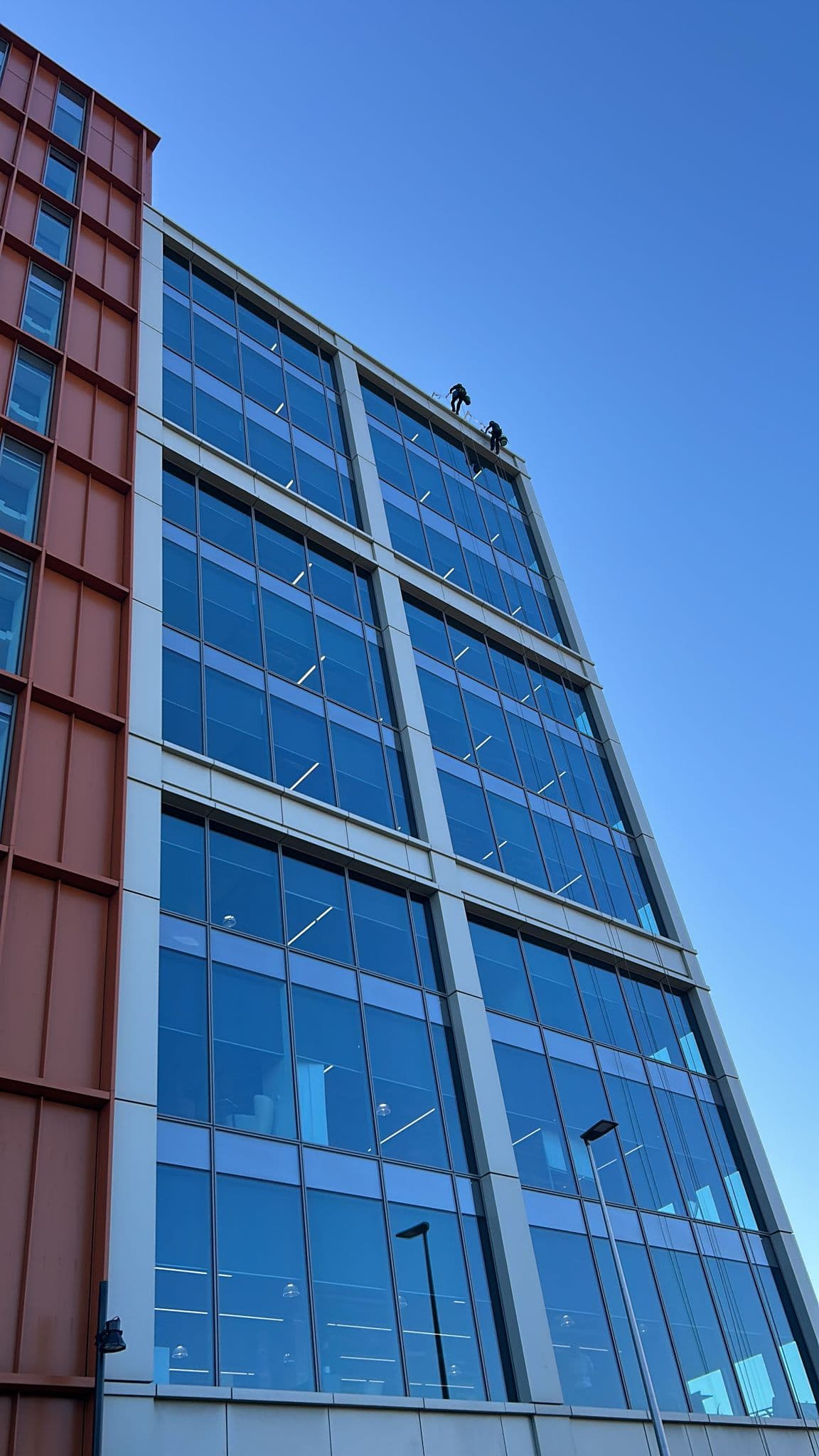 Rope access window cleaning on a glass office facade