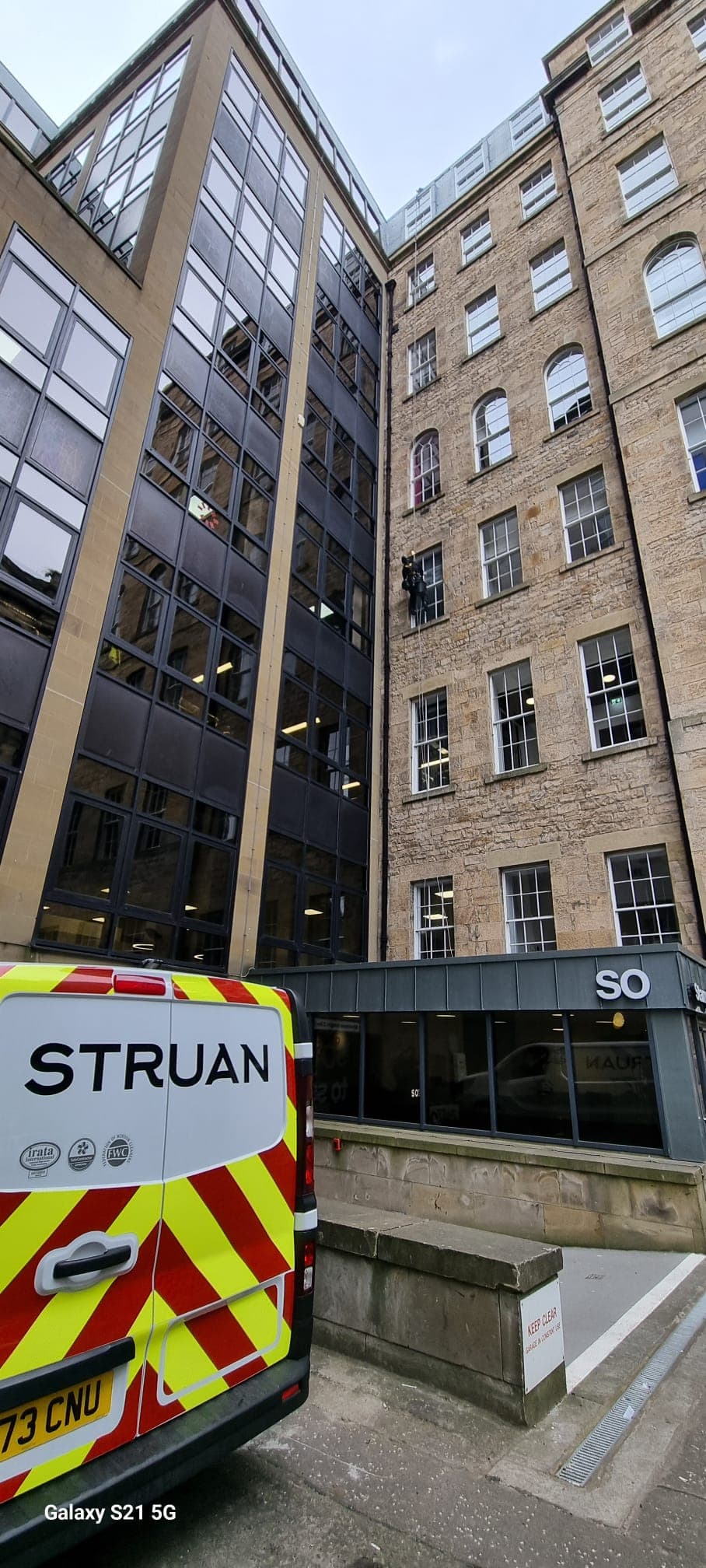 Struan van with IRATA logos and rope access technician working on building above